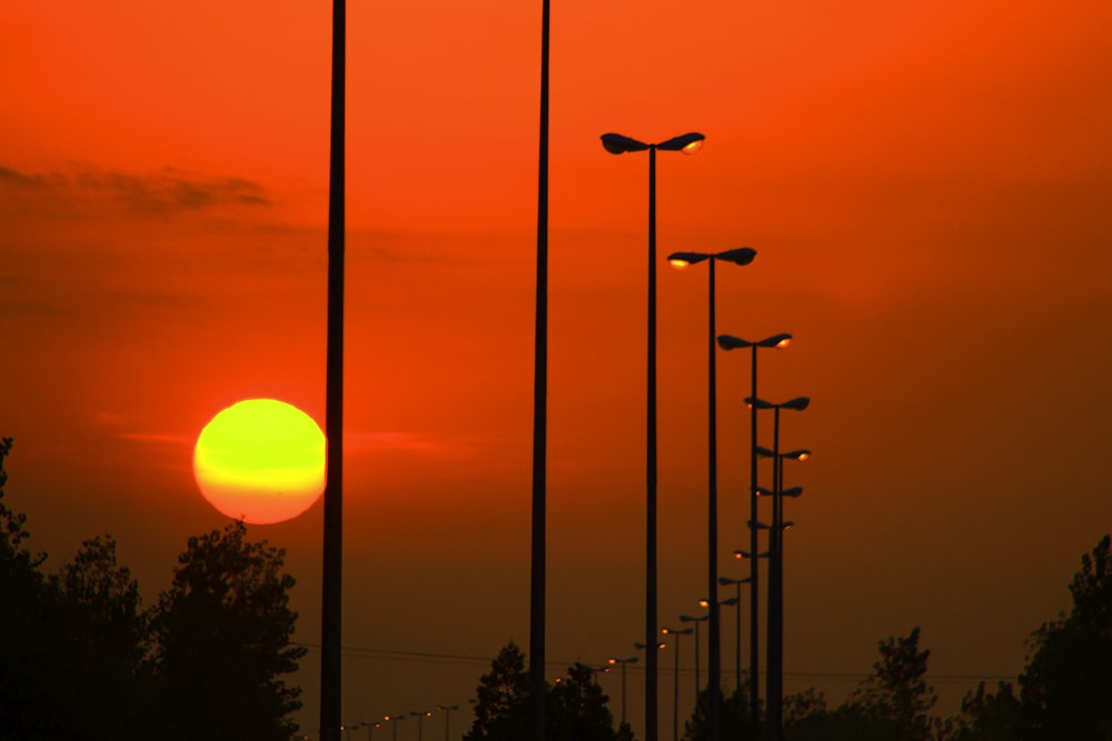 a row of street lights with the sun setting in the background
