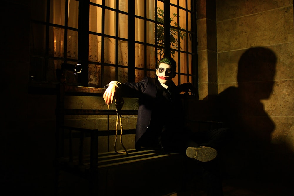 a man in a suit and mask sitting on a window sill