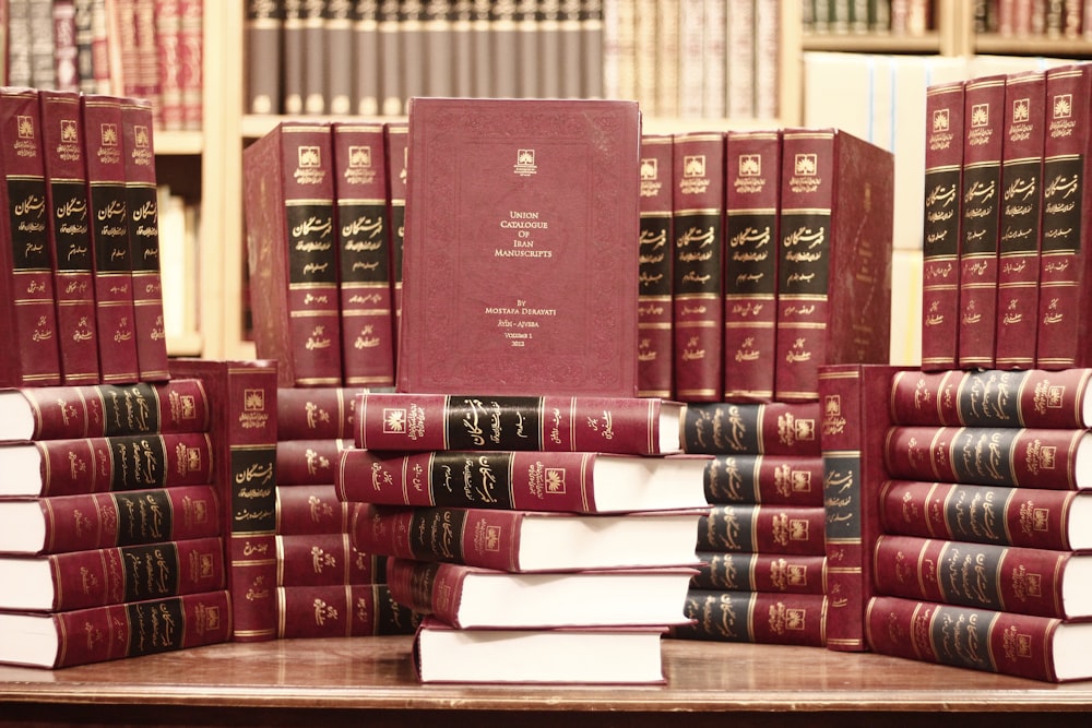 a stack of red books sitting on top of a wooden table