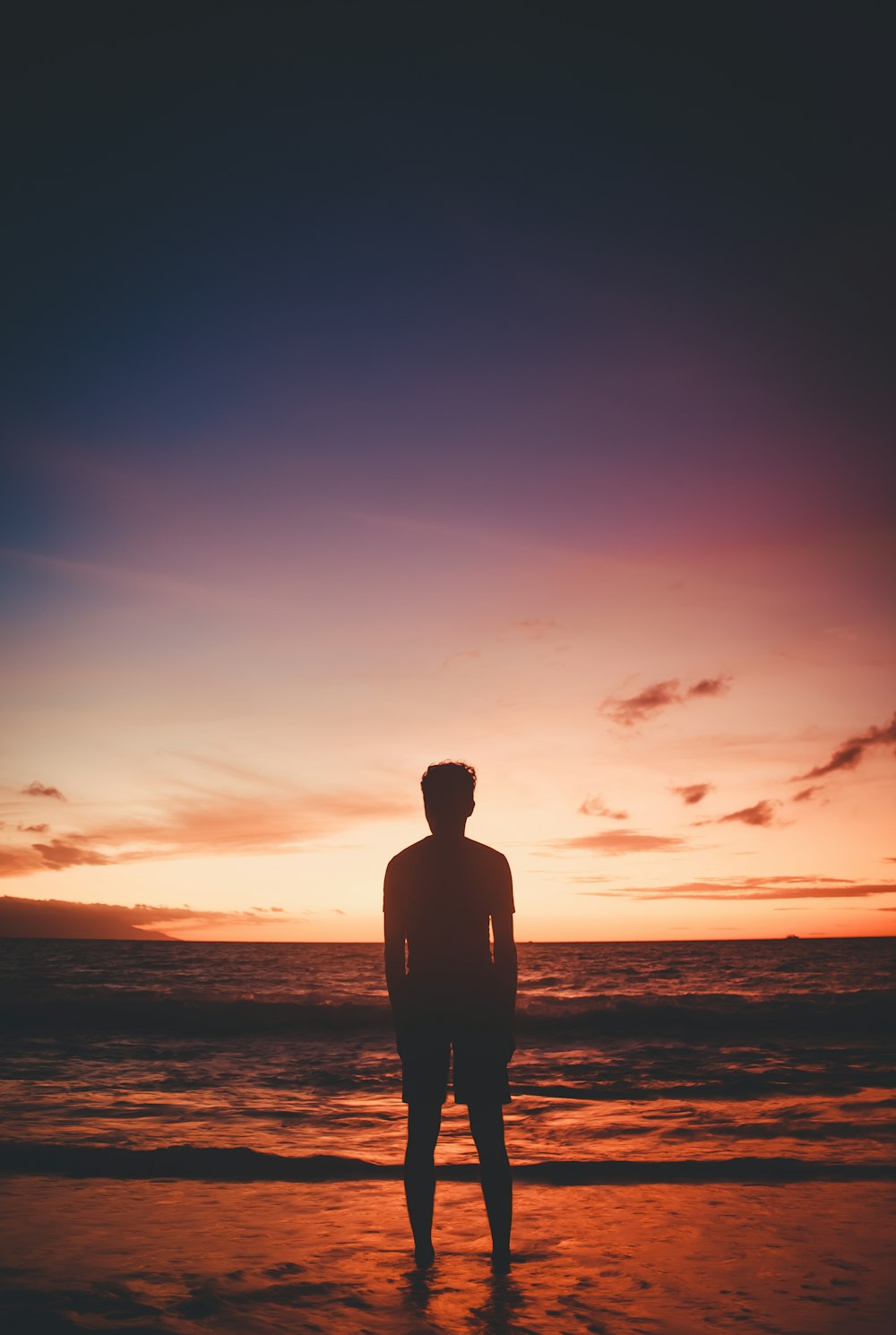 a man standing on top of a beach next to the ocean