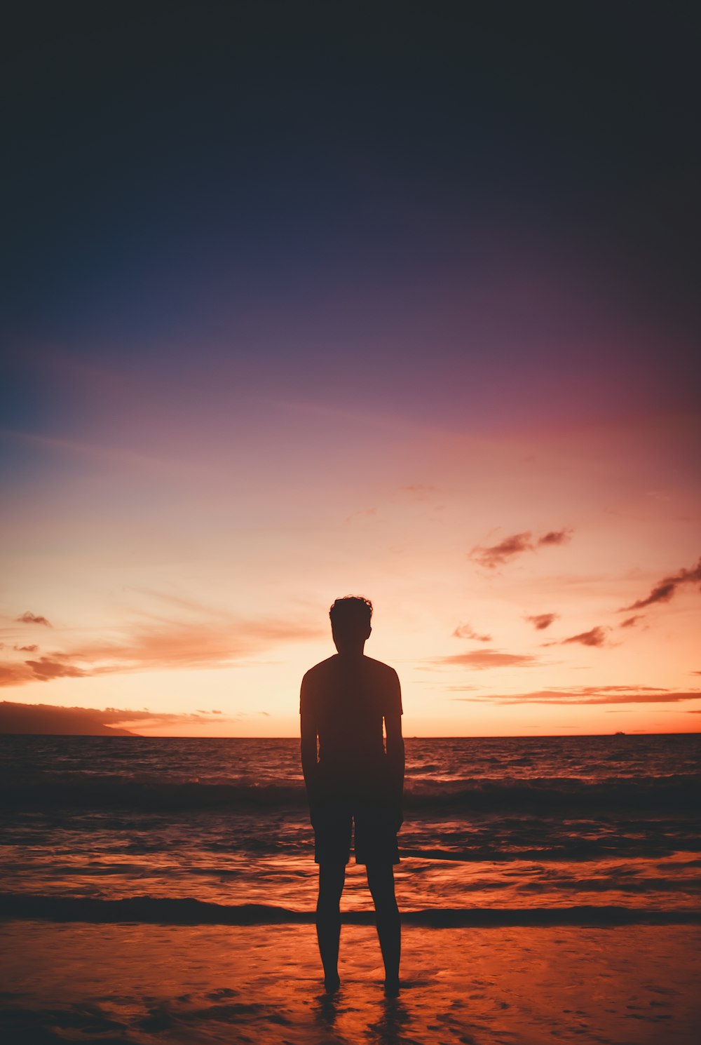 um homem em pé no topo de uma praia ao lado do oceano