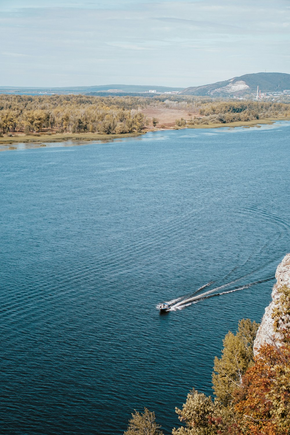 a boat traveling down a river next to a forest