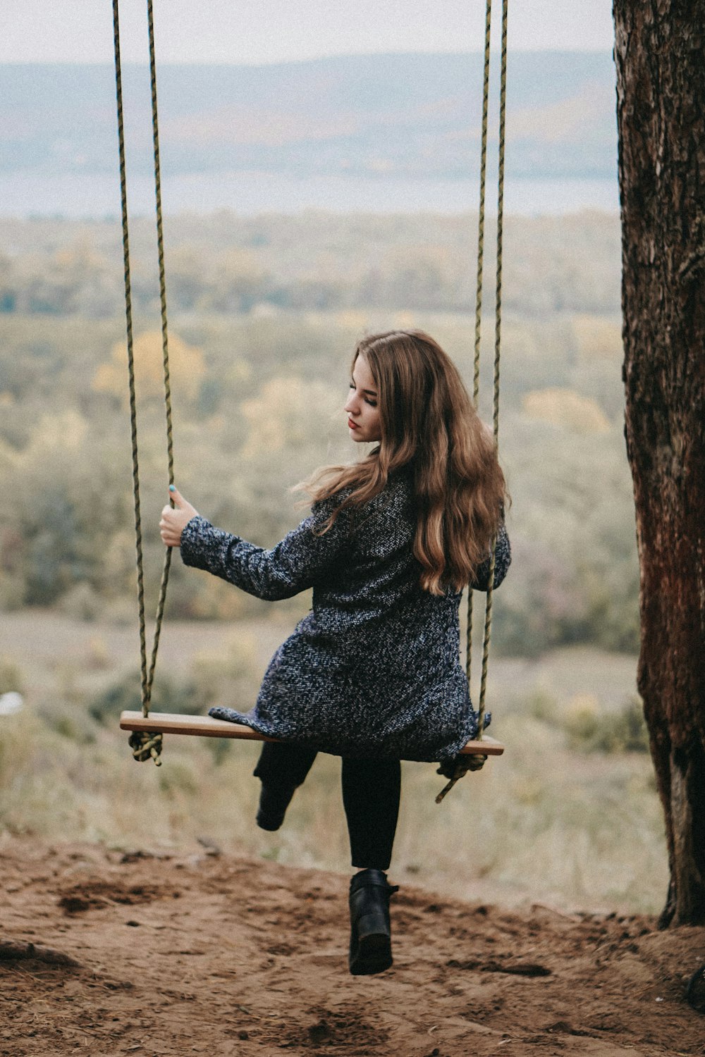 a woman sitting on a swing in a tree