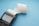 A close-up view of a black electronic card reader with a spool of white receipt paper extending from it, set against a light blue background.