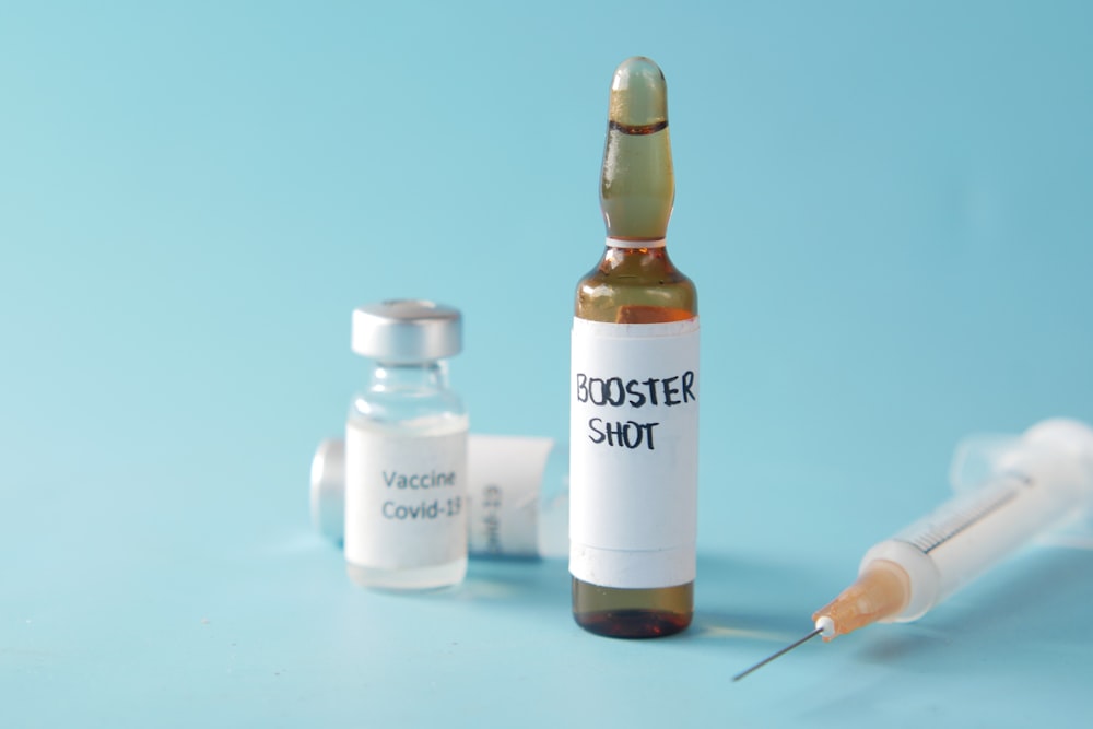 a bottle of booster shot next to a syringe