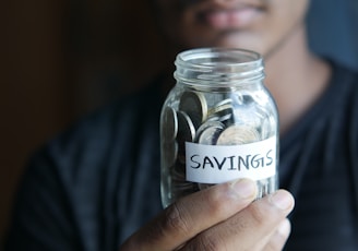 a man holding a jar with a savings label on it