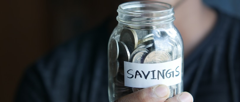a man holding a jar with a savings label on it