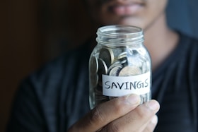 man holding a jar with the word savings on it for gold ira retirement savings blog post