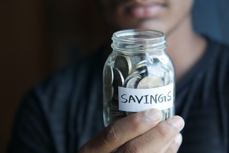 A man holding a jar with a savings label on it – financial freedom, budgeting tips, wealth building.