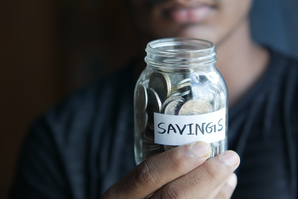 a man holding a jar with a savings label on it