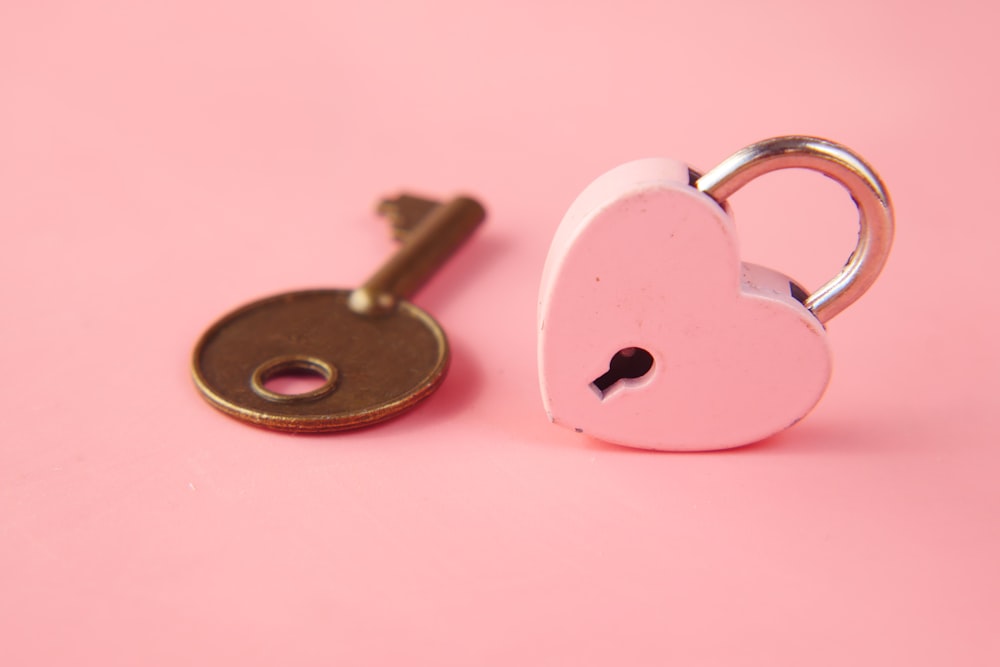 une serrure en forme de cœur et une clé sur fond rose