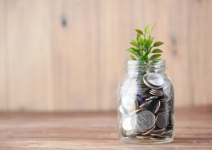 a glass jar filled with coins and a plant