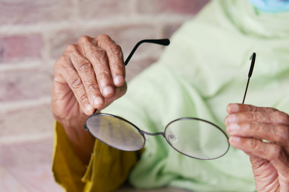uma mulher idosa segurando um par de óculos