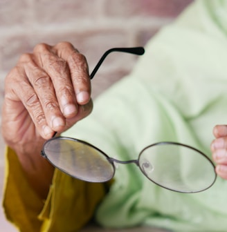 an elderly woman holding a pair of glasses