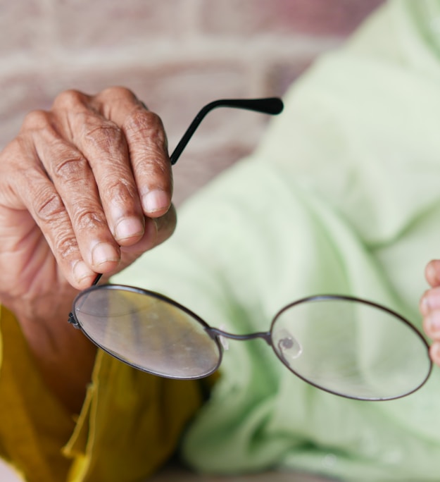 an elderly woman holding a pair of glasses