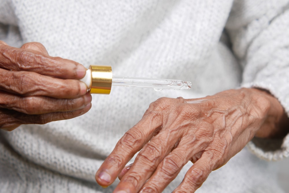 uma mulher mais velha segurando um pequeno tubo de líquido