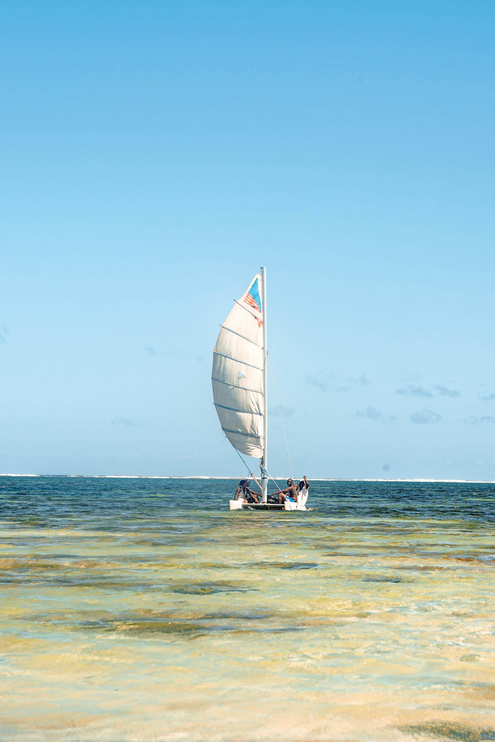 a sailboat with two people on it in the ocean