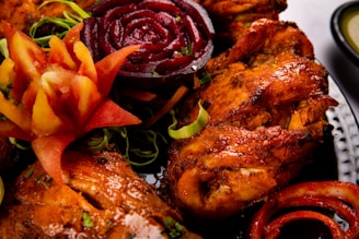 A platter of cooked chicken dishes garnished attractively.