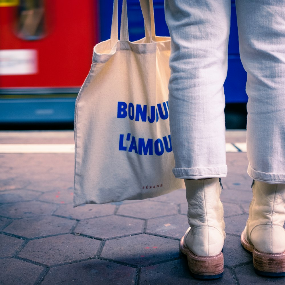 a person holding a white bag with blue writing on it