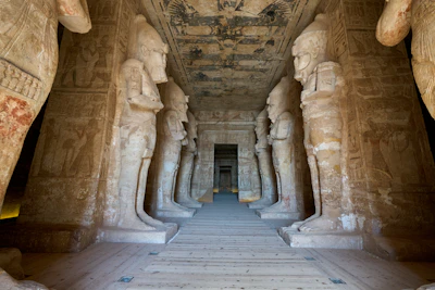 Ancient statues of deities lined up in a dimly lit temple hall.