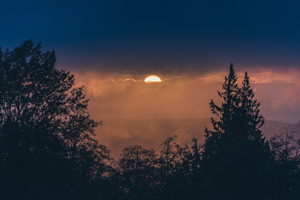 the sun is setting behind some trees