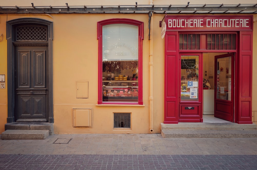 a yellow building with a red door and window