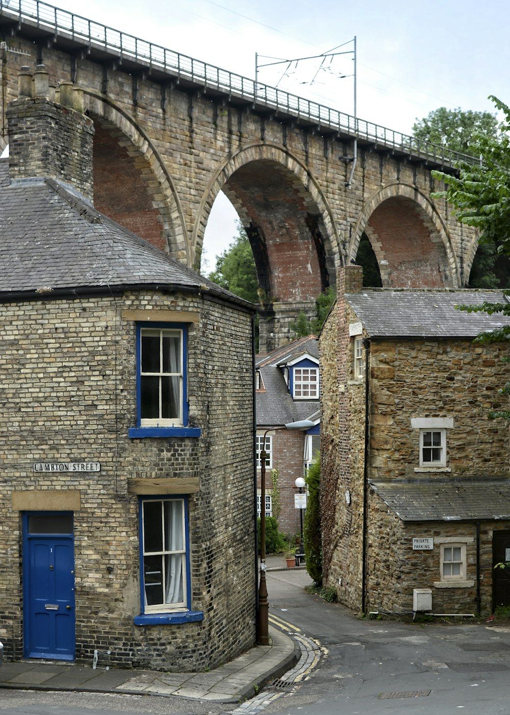 a brick building with a blue door and a bridge in the background