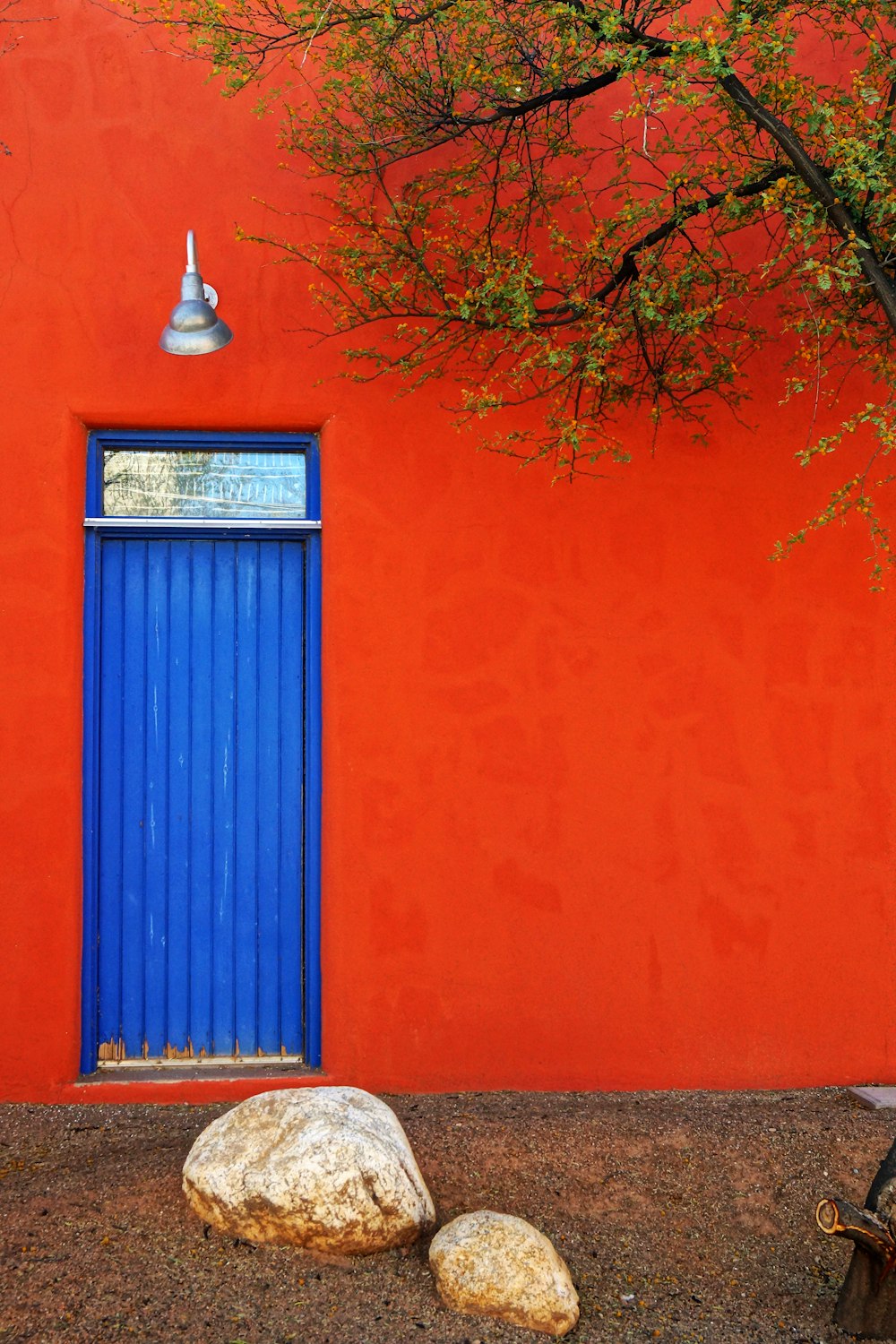 a red building with a blue door and a tree