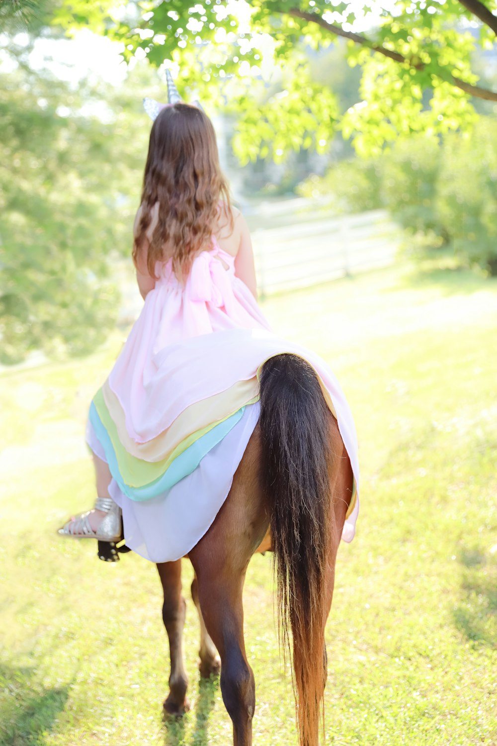 a little girl riding on the back of a brown horse
