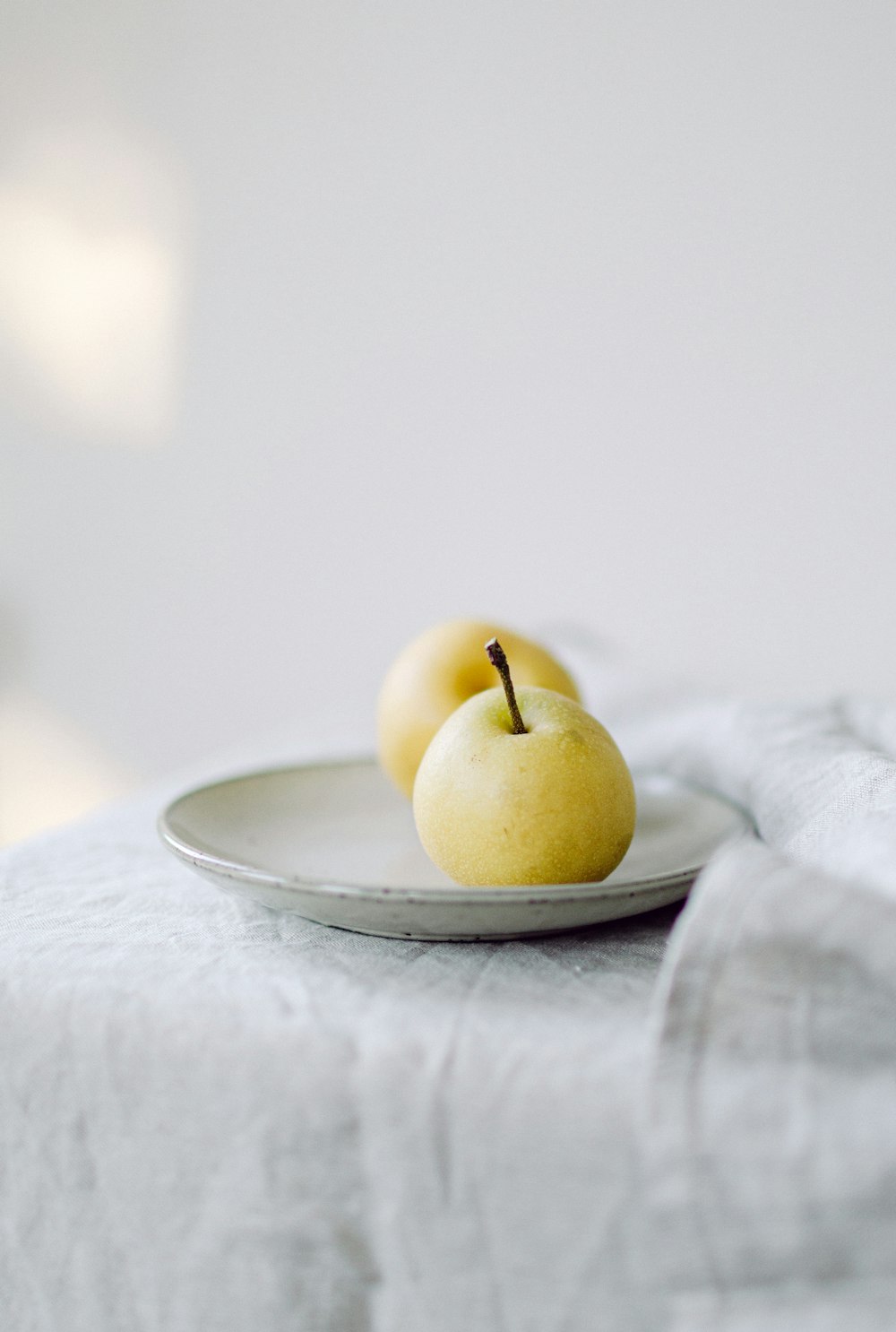 two apples sitting on a plate on a table
