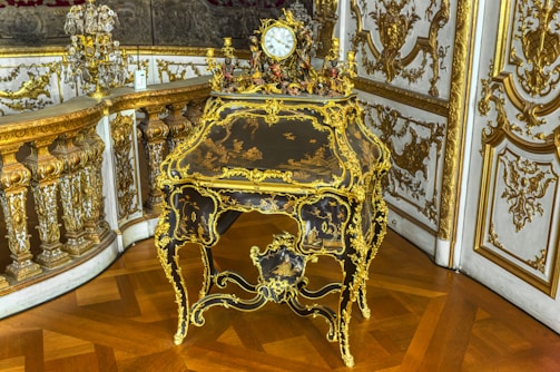 Close-up of a polished antique office desk with intricate carvings and brass handles.