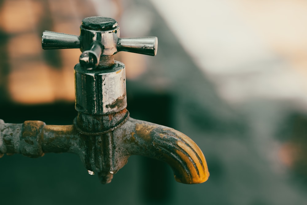 a close up of a metal faucet with water dripping from it