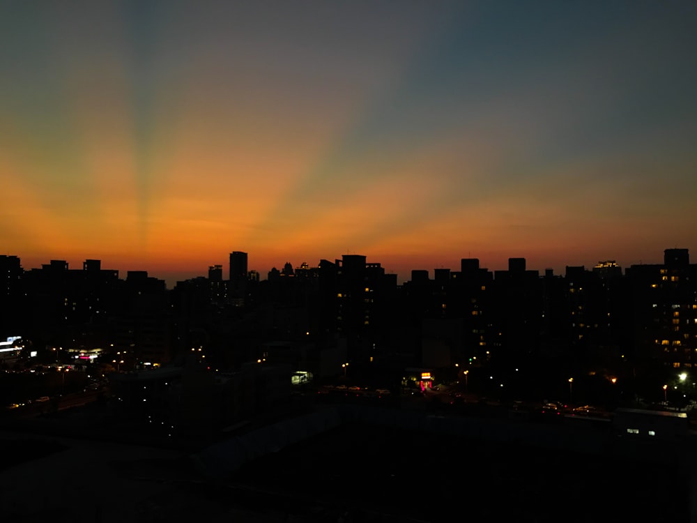 the sun is setting over a city with tall buildings