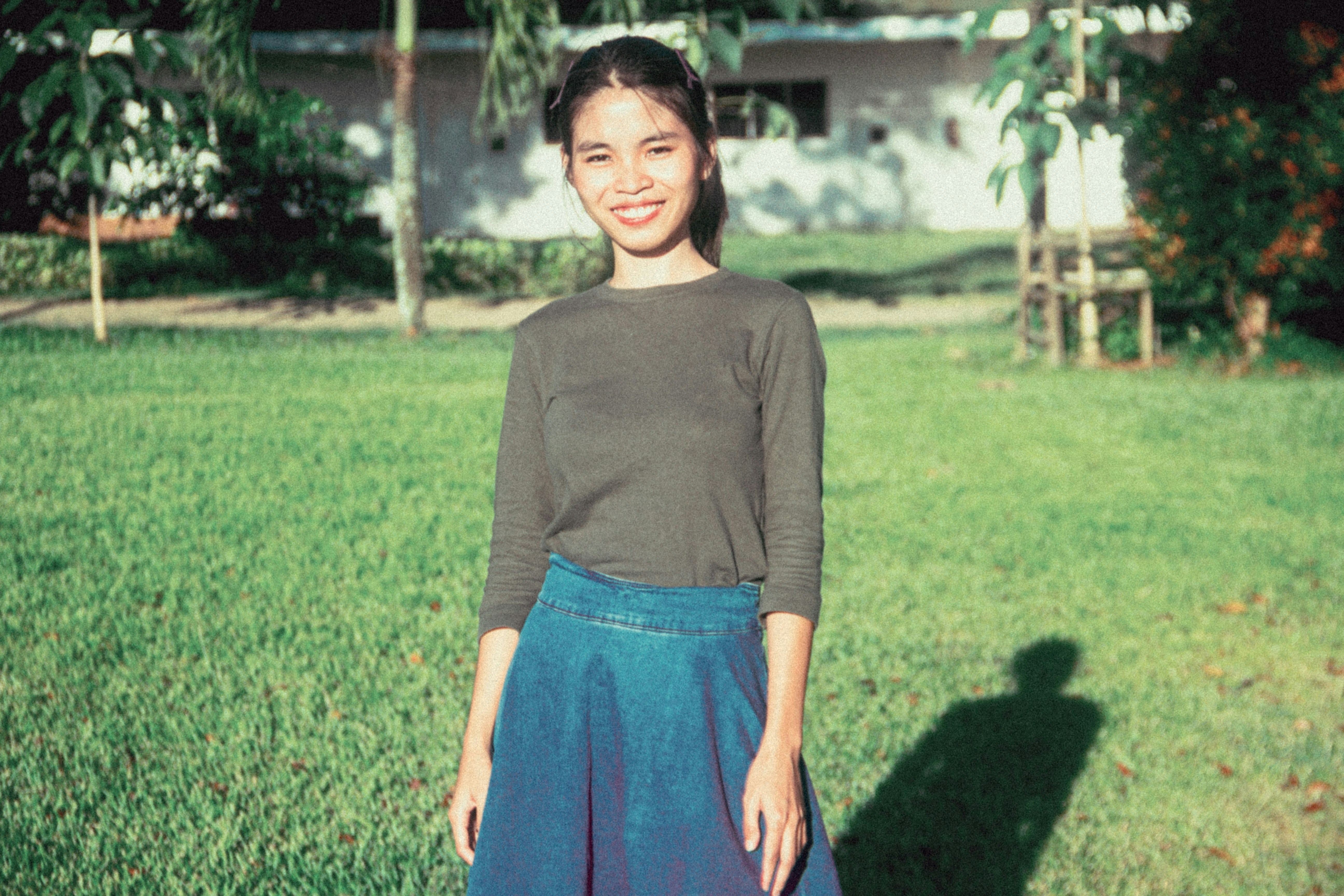 a woman standing in the grass in front of a house