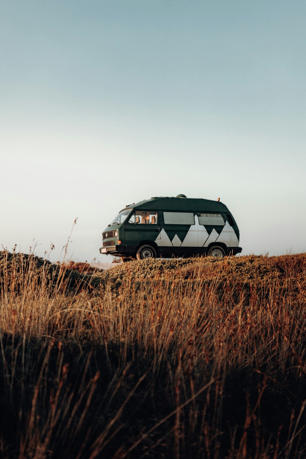 a van parked on top of a grass covered hill