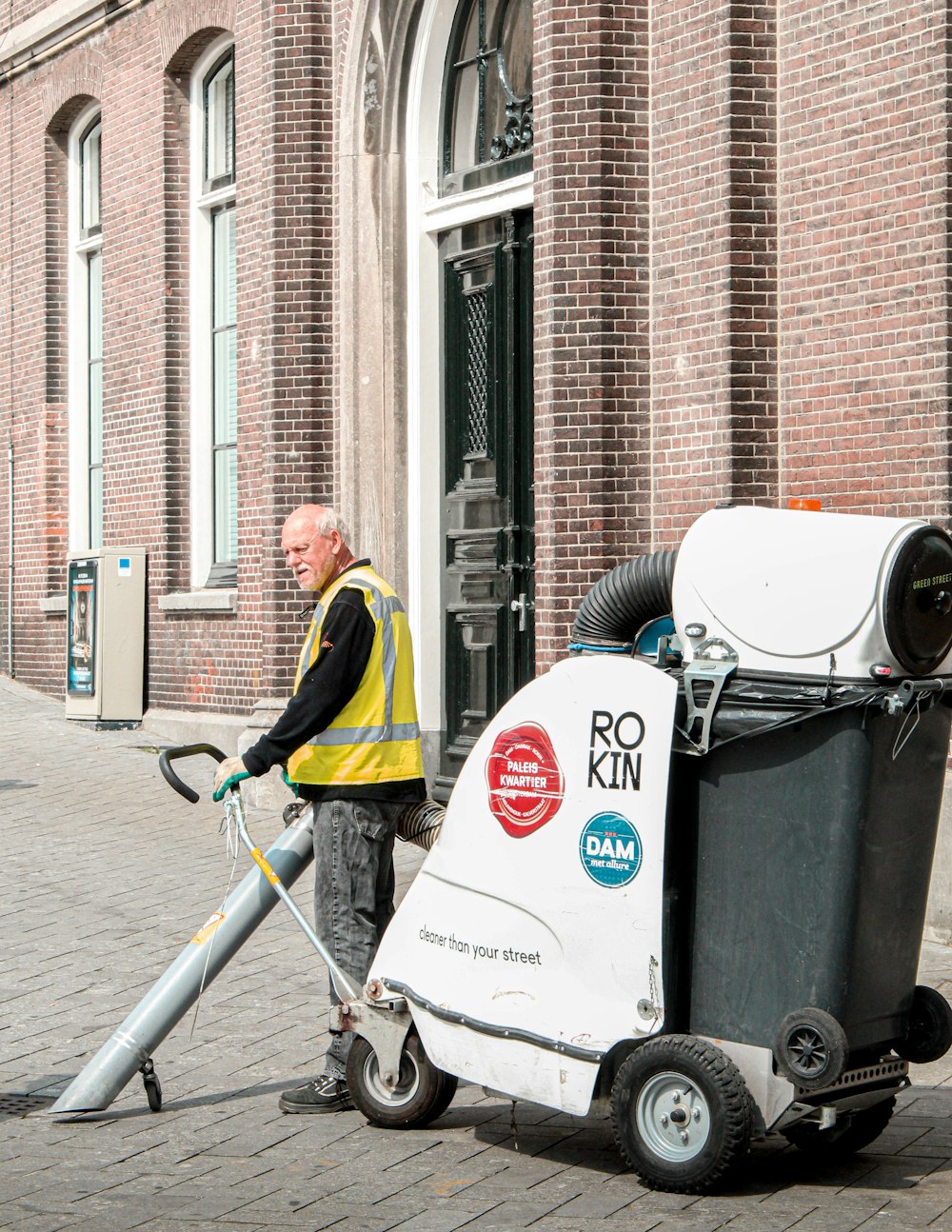 Un homme en gilet jaune nettoie une rue