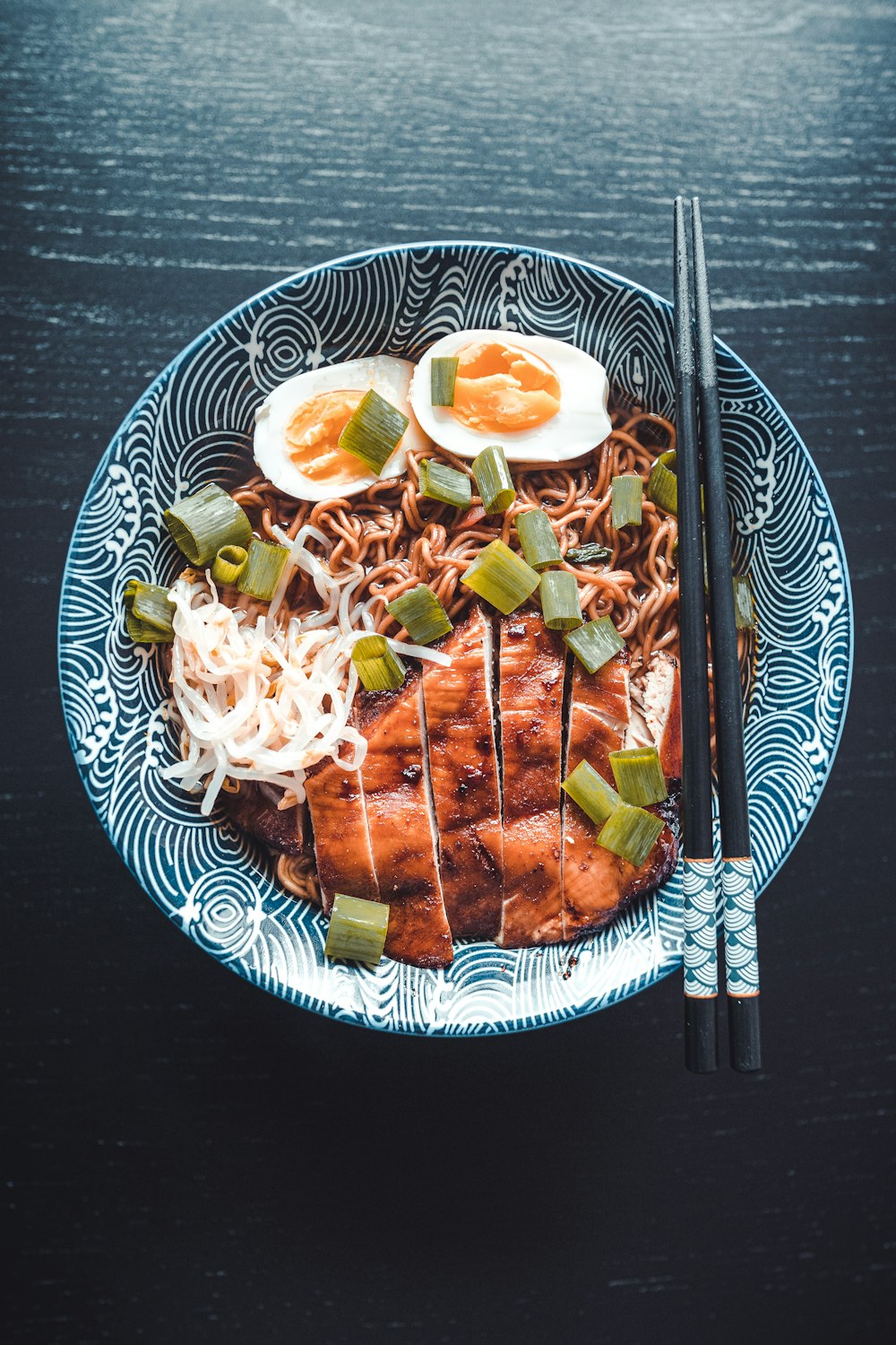 a blue and white plate topped with meat and noodles