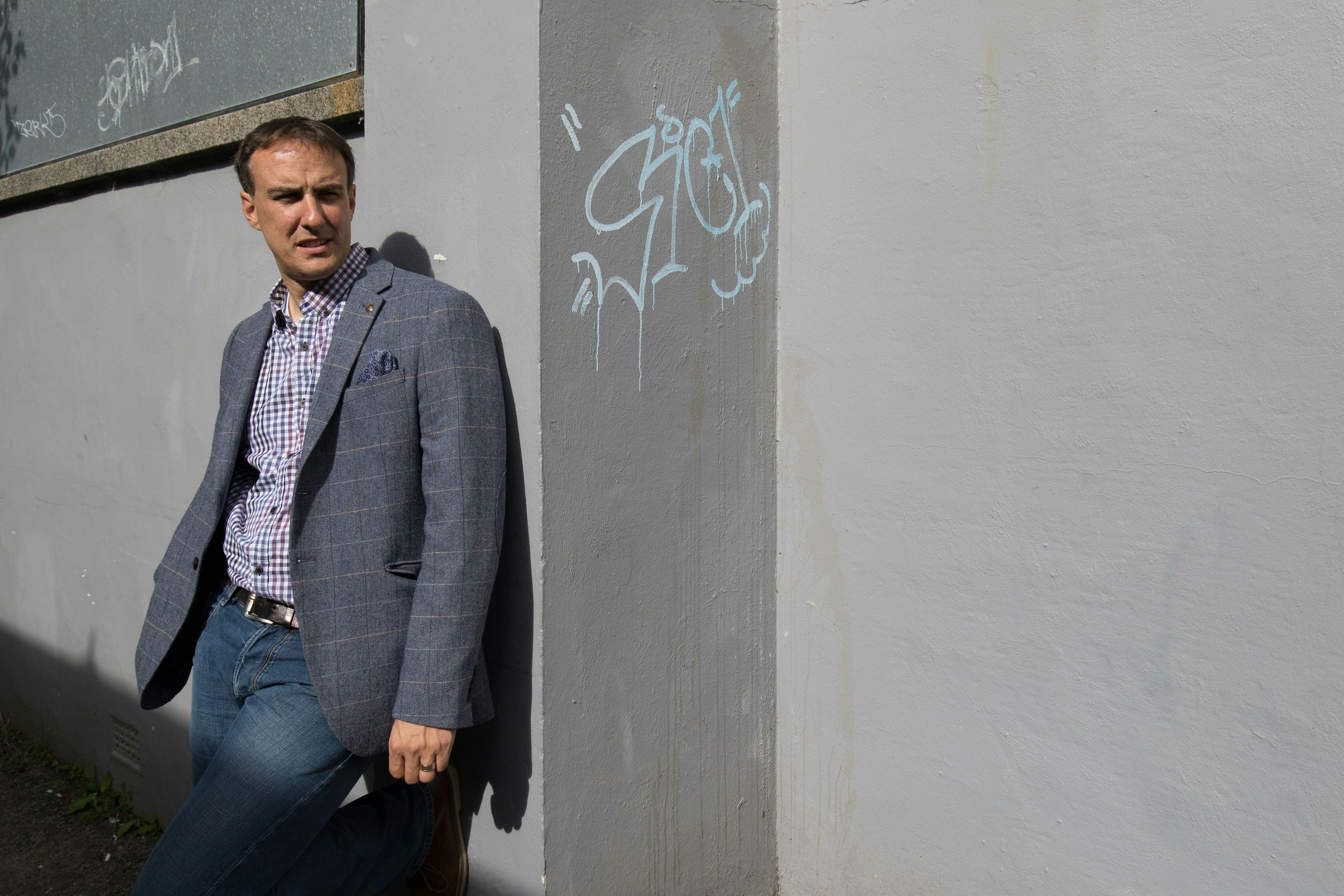 a man leaning against a wall with graffiti on it