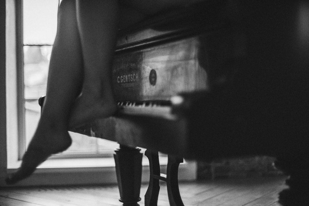 a black and white photo of a person's legs on a piano