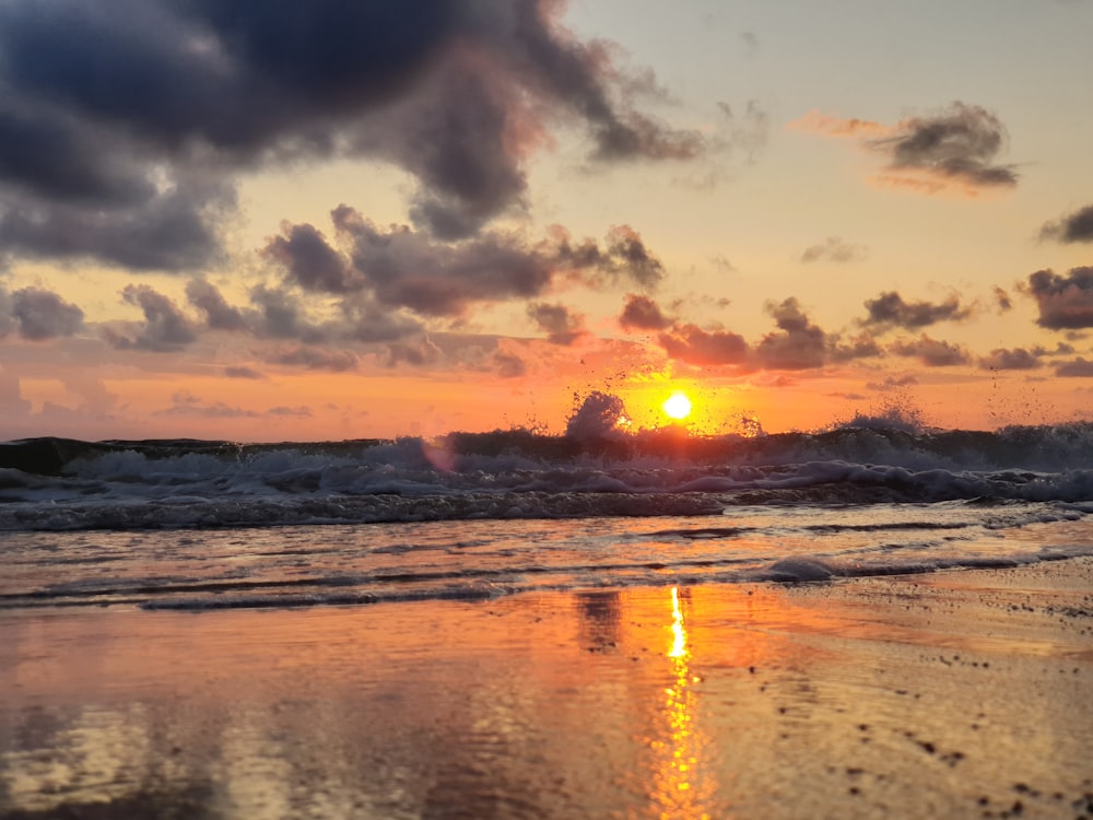 the sun is setting over the ocean waves