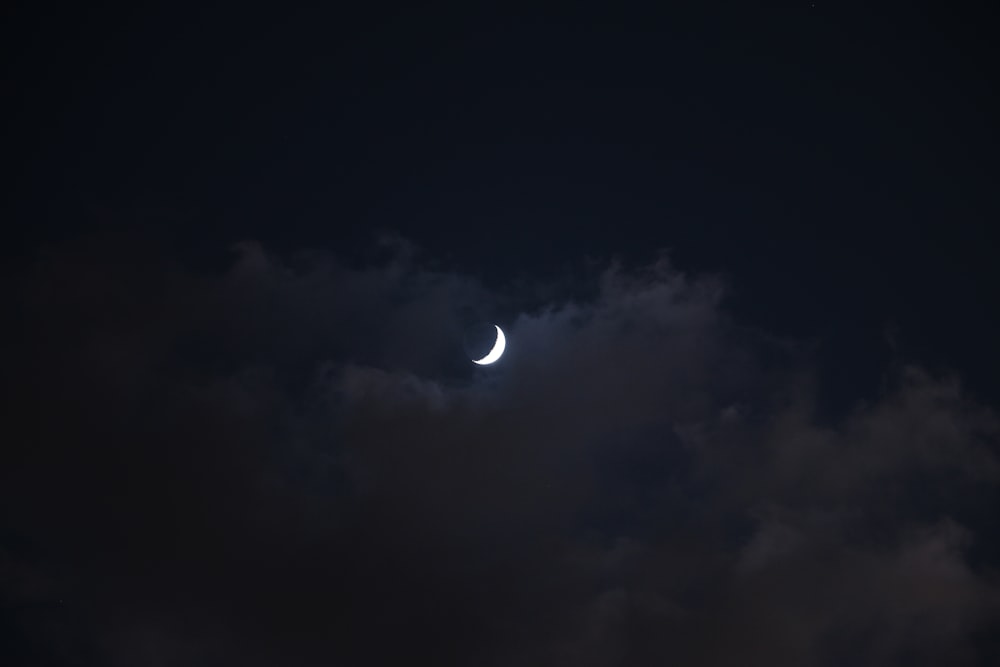 the moon is seen through the clouds in the night sky