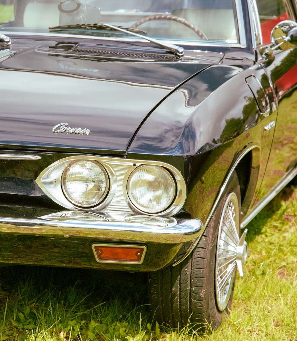 a black car parked on top of a lush green field