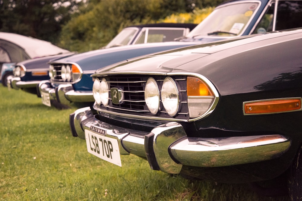 a row of parked cars sitting on top of a lush green field