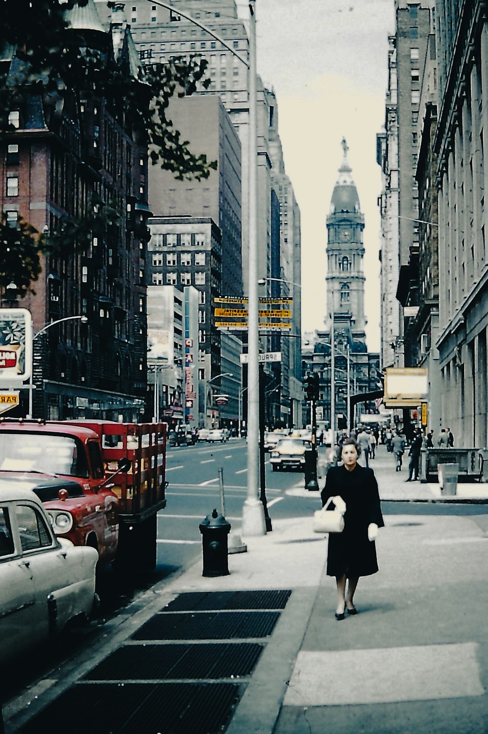 a woman walking down a street next to tall buildings