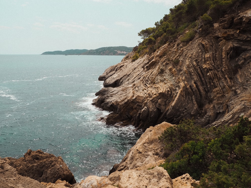 a large body of water sitting next to a rocky cliff