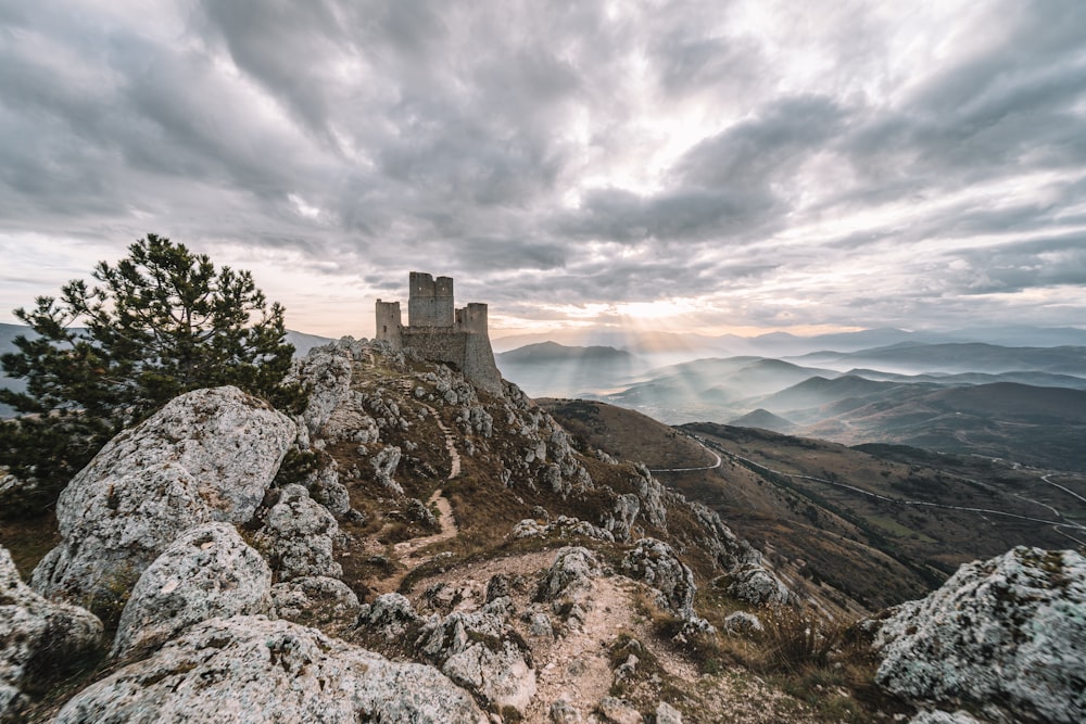 a castle on top of a mountain under a cloudy sky