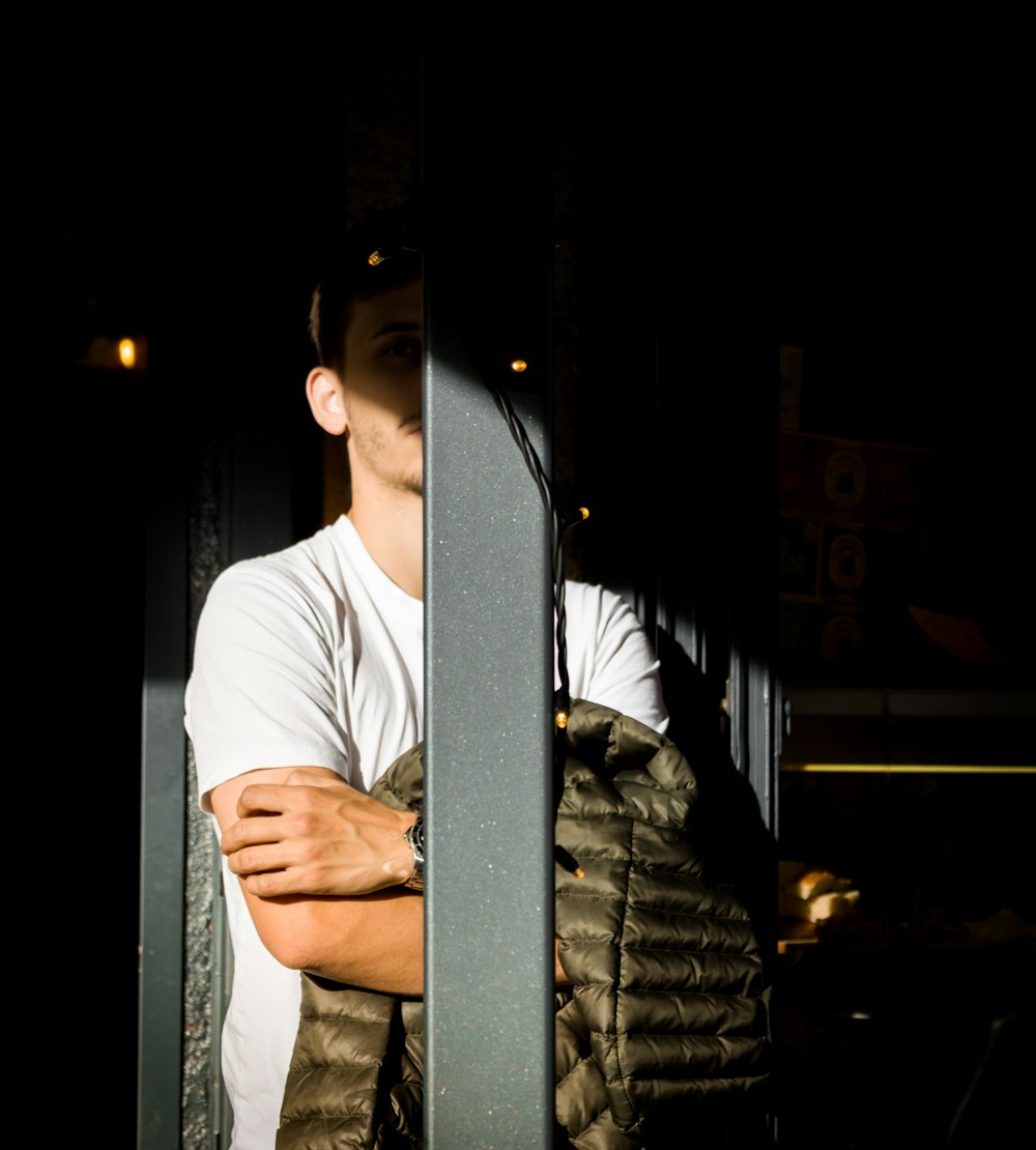 a man standing behind a metal fence with his arms crossed