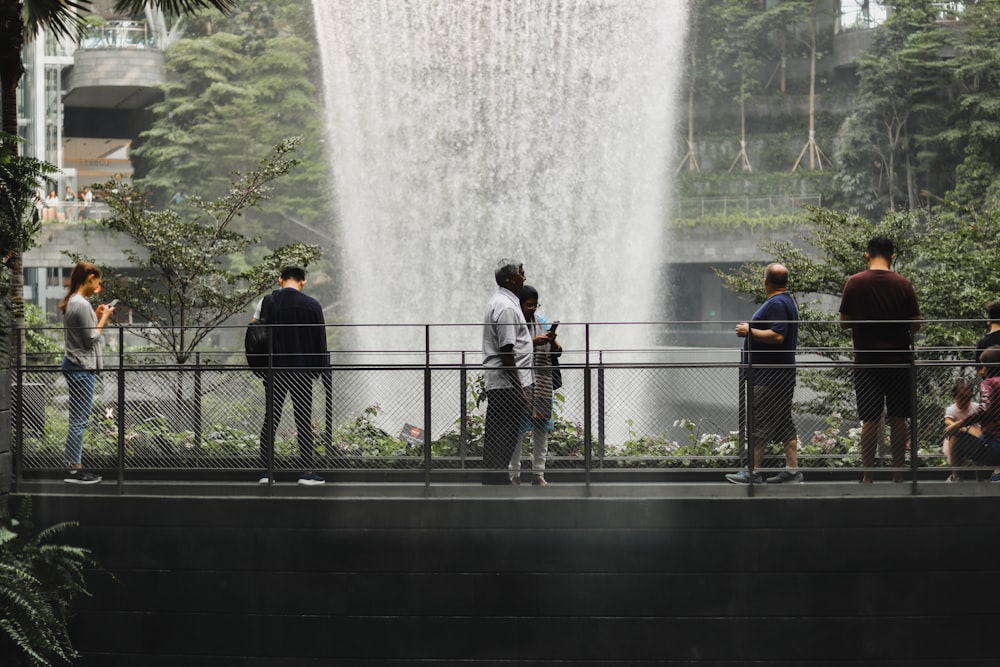 a group of people standing next to a waterfall