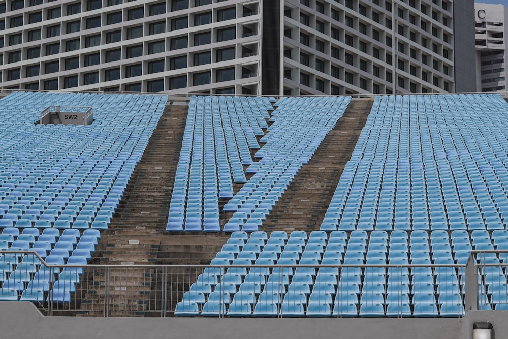 Un estadio lleno de asientos azules junto a un edificio alto