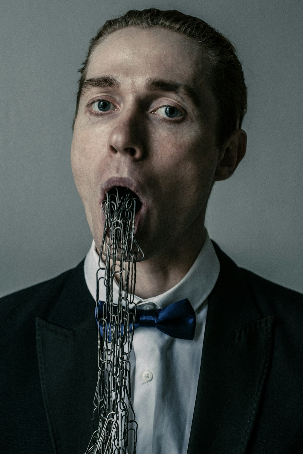 a man in a tuxedo is eating a piece of metal